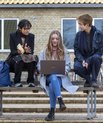 Three students sitting on a bench and studying.